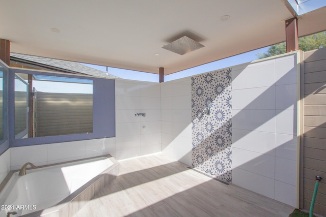 bathroom featuring hardwood / wood-style floors, a healthy amount of sunlight, and tile walls