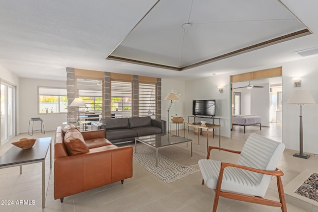 tiled living room featuring a raised ceiling and ceiling fan