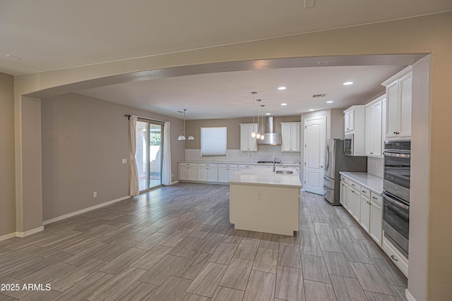 3796 E Rakestraw Ln, Gilbert, AZ 85298 - kitchen with wall chimney exhaust hood, decorative backsplash, an island with sink, appliances with stainless steel finishes, and light wood-type flooring