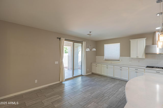 3796 E Rakestraw Ln, Gilbert, AZ 85298 - kitchen with wall chimney exhaust hood, decorative backsplash, gas cooktop, white cabinets, and light countertops