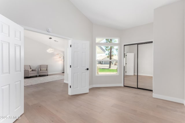 unfurnished bedroom featuring baseboards, light wood-type flooring, and high vaulted ceiling