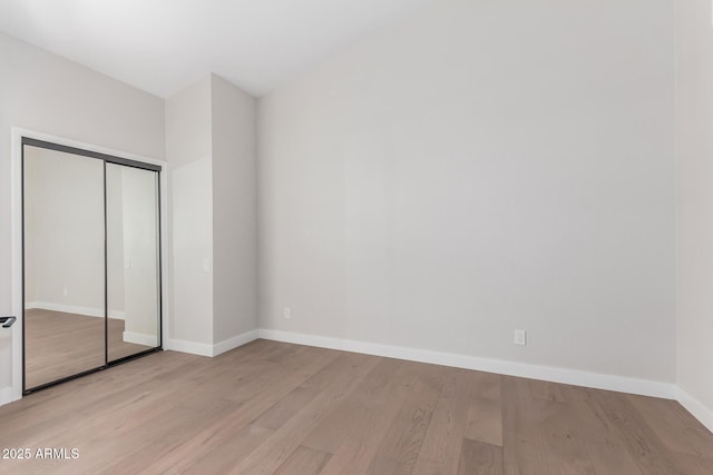 unfurnished bedroom featuring a closet, baseboards, and light wood-style flooring