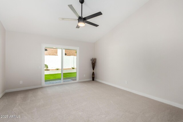 empty room featuring light carpet, ceiling fan, baseboards, and vaulted ceiling
