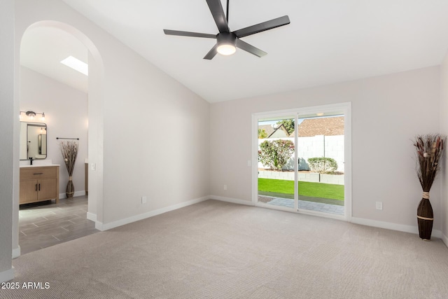 unfurnished room featuring arched walkways, light colored carpet, lofted ceiling, and a ceiling fan