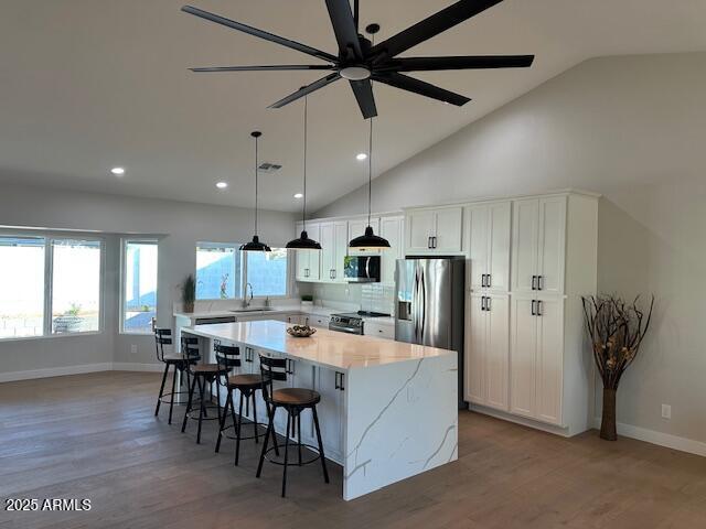 kitchen featuring a center island, white cabinets, stainless steel appliances, and a sink