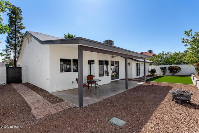 back of property with a patio, stucco siding, a fenced backyard, and a fire pit