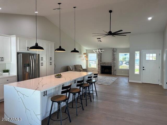 kitchen featuring a brick fireplace, ceiling fan, stainless steel fridge with ice dispenser, and white cabinetry