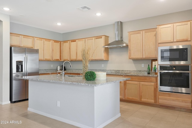 kitchen featuring light stone counters, stainless steel appliances, sink, wall chimney range hood, and light brown cabinets