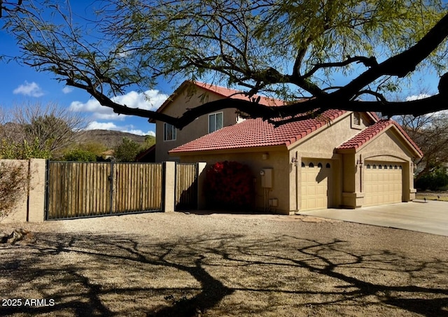 view of front facade featuring fence, driveway, an attached garage, stucco siding, and a tile roof