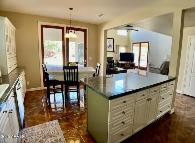 kitchen featuring dark countertops, baseboards, decorative light fixtures, ceiling fan with notable chandelier, and white cabinetry