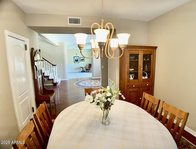 dining room featuring stairway, baseboards, visible vents, dark wood-type flooring, and a notable chandelier