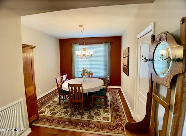 dining area featuring wood finished floors, a notable chandelier, baseboards, and visible vents