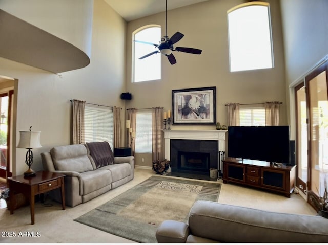 living area with a ceiling fan, plenty of natural light, a fireplace, and carpet floors