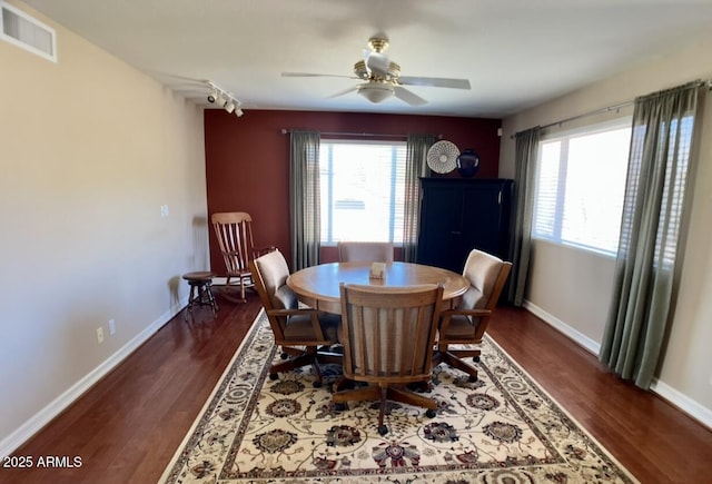 dining space featuring visible vents, baseboards, dark wood-style floors, and a ceiling fan