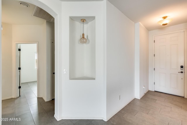 foyer entrance with arched walkways, visible vents, and baseboards