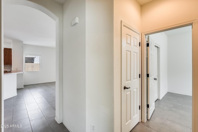 corridor featuring arched walkways and tile patterned flooring