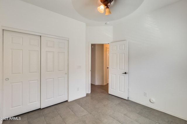 unfurnished bedroom with a ceiling fan, a closet, and baseboards