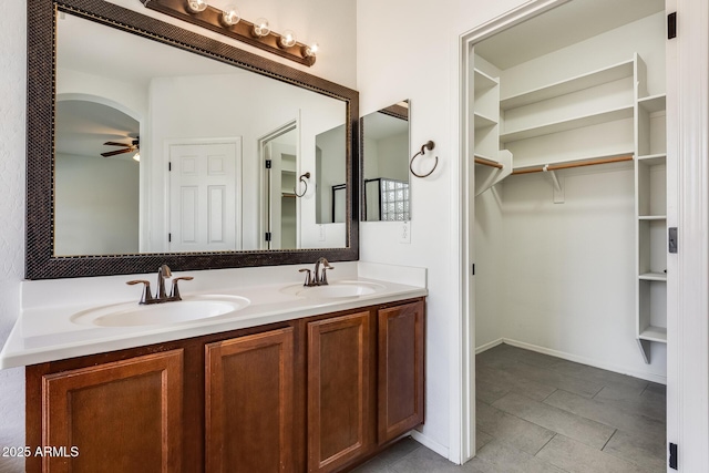 full bathroom with double vanity, a spacious closet, a sink, and a ceiling fan