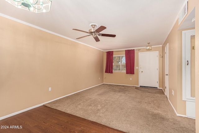 spare room featuring wood-type flooring, ceiling fan with notable chandelier, and ornamental molding