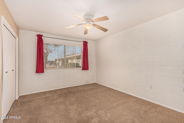 empty room with carpet flooring, ceiling fan, and brick wall