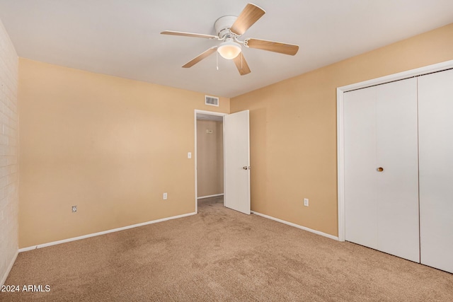 unfurnished bedroom featuring ceiling fan, light colored carpet, and a closet