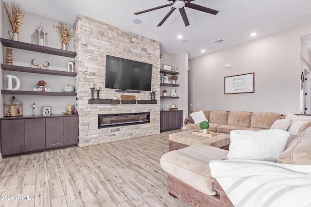 living room featuring a stone fireplace, ceiling fan, built in features, and light hardwood / wood-style floors