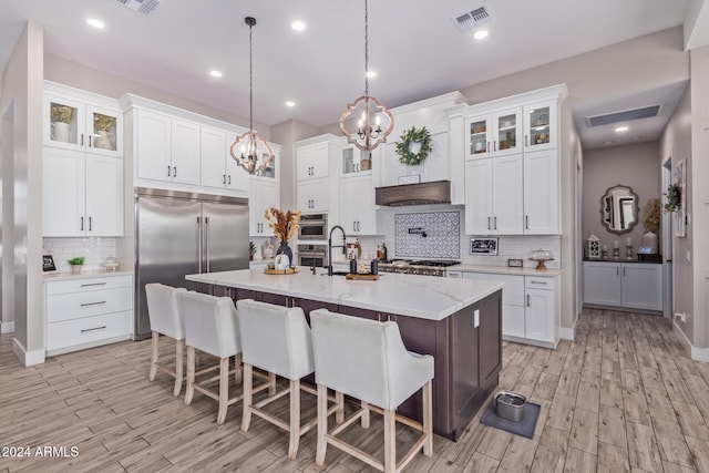 kitchen with white cabinetry, a center island with sink, decorative light fixtures, and appliances with stainless steel finishes