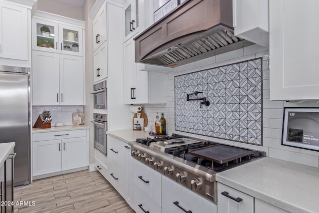 kitchen with decorative backsplash, light wood-type flooring, white cabinetry, and stainless steel appliances