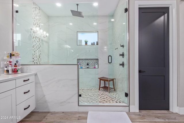 bathroom featuring tile walls, vanity, wood-type flooring, and a shower with shower door