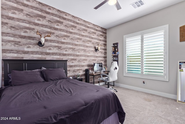 carpeted bedroom with ceiling fan and wooden walls