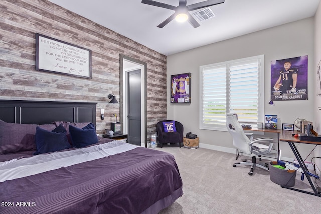 carpeted bedroom with ceiling fan and wood walls