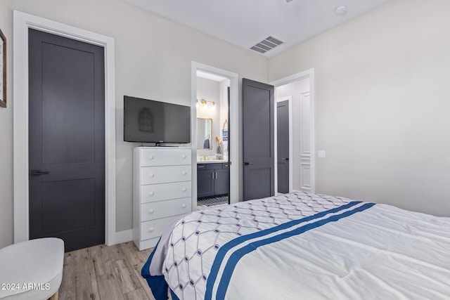 bedroom featuring ensuite bath and light hardwood / wood-style flooring