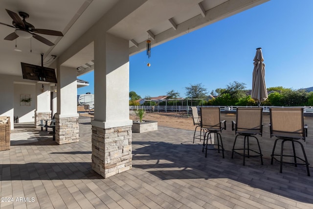 view of patio featuring ceiling fan and a bar