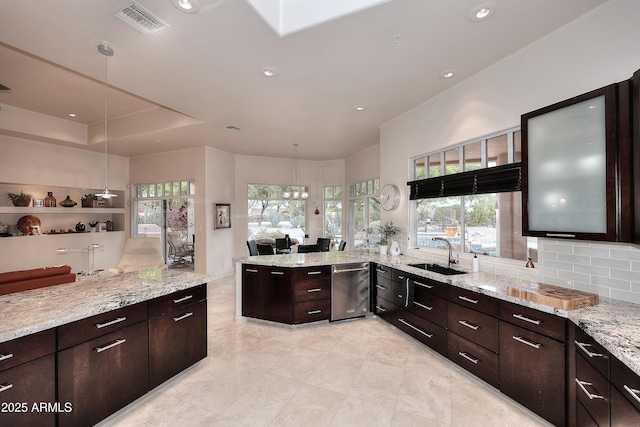 kitchen with a peninsula, a wealth of natural light, visible vents, and a sink
