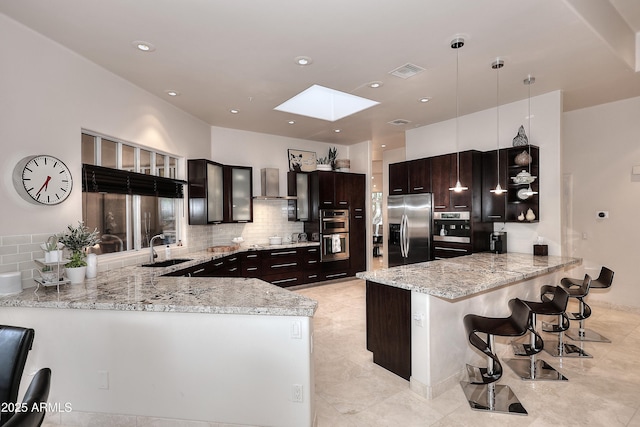kitchen with a peninsula, a sink, stainless steel appliances, a skylight, and visible vents