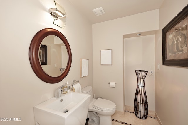 half bath featuring a sink, toilet, visible vents, tile patterned flooring, and baseboards