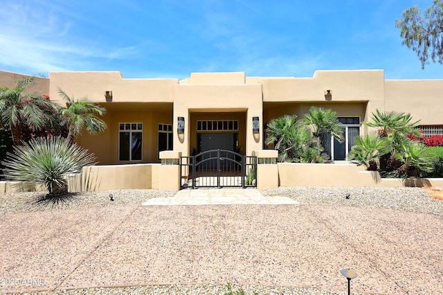 adobe home featuring stucco siding and a gate