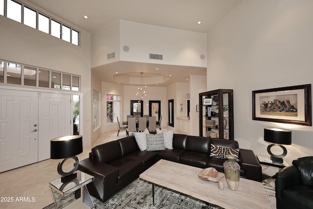 living area with light tile patterned floors, visible vents, and a high ceiling