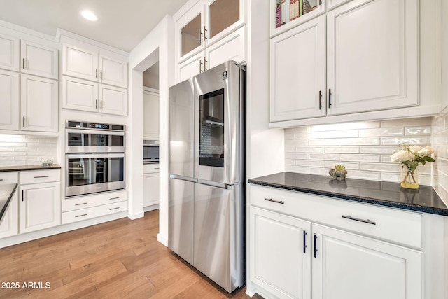 3417 E Los Gatos Dr, Phoenix, AZ 85050 - kitchen featuring stainless steel appliances, white cabinets, backsplash, glass insert cabinets, and light wood-style floors