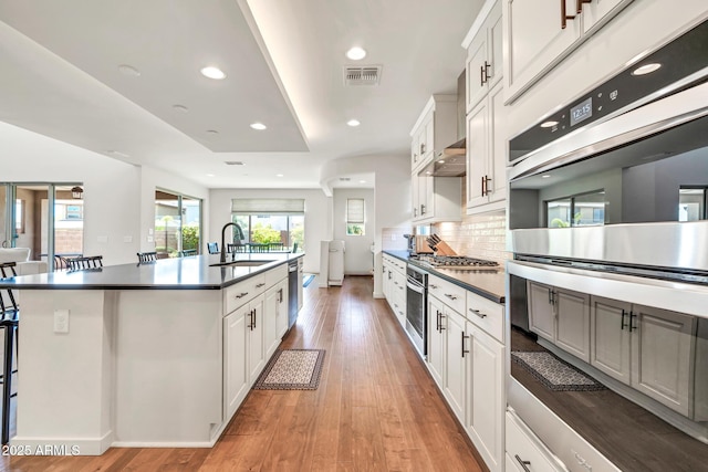 3417 E Los Gatos Dr, Phoenix, AZ 85050 - kitchen featuring stainless steel appliances, dark countertops, a center island with sink, recessed lighting, and tasteful backsplash