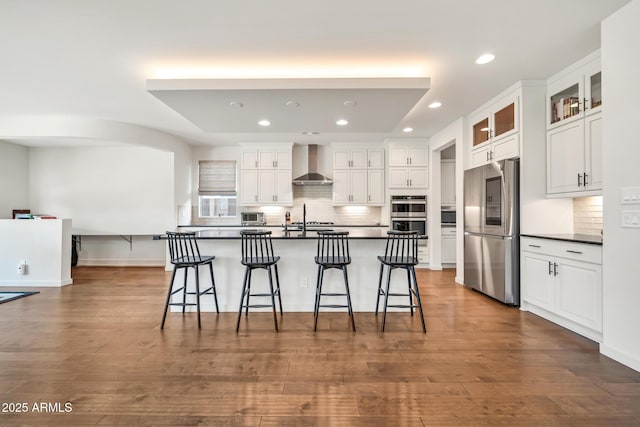 3417 E Los Gatos Dr, Phoenix, AZ 85050 - kitchen featuring appliances with stainless steel finishes, wall chimney range hood, dark countertops, recessed lighting, and a kitchen breakfast bar