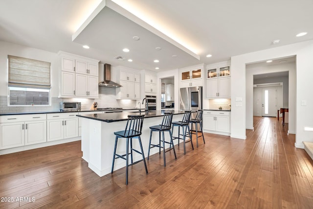 3417 E Los Gatos Dr, Phoenix, AZ 85050 - kitchen featuring wall chimney exhaust hood, stainless steel appliances, dark countertops, a kitchen breakfast bar, and decorative backsplash