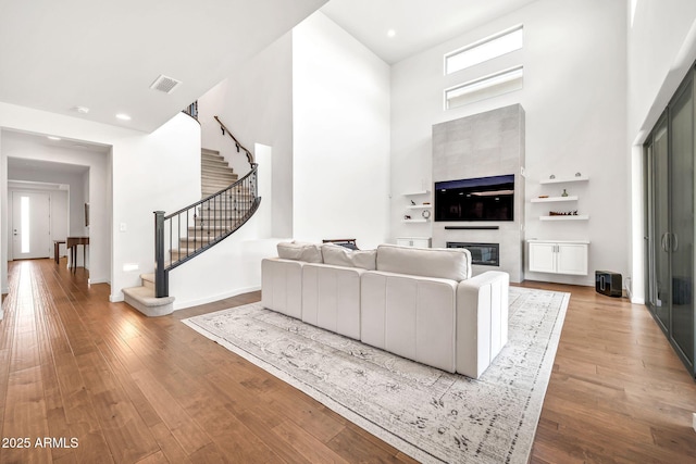 3417 E Los Gatos Dr, Phoenix, AZ 85050 - living room featuring a towering ceiling, stairs, wood finished floors, a glass covered fireplace, and recessed lighting