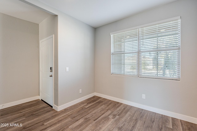 empty room with dark wood-type flooring and a wealth of natural light