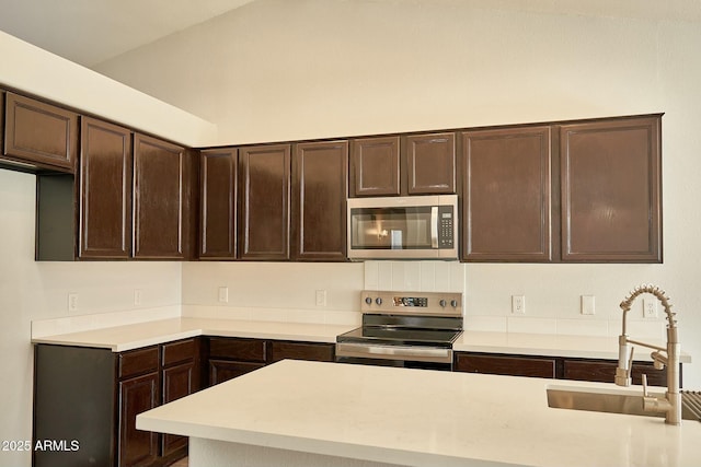 kitchen featuring a sink, dark brown cabinets, stainless steel appliances, and light countertops