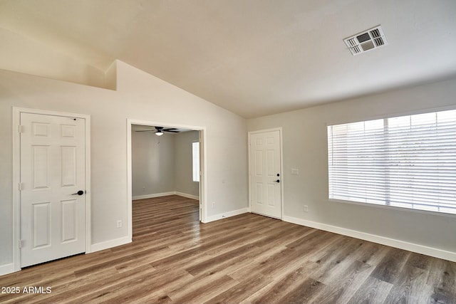 spare room with visible vents, vaulted ceiling, baseboards, and wood finished floors