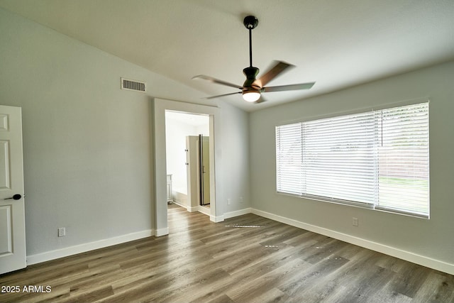 empty room with lofted ceiling, baseboards, visible vents, and wood finished floors