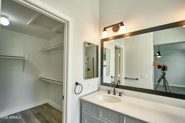 bathroom featuring a spacious closet, wood finished floors, vanity, and baseboards