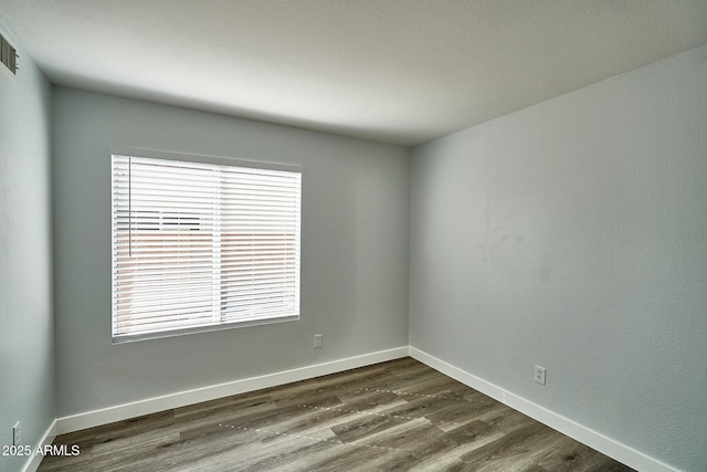 spare room with dark wood-style flooring and baseboards