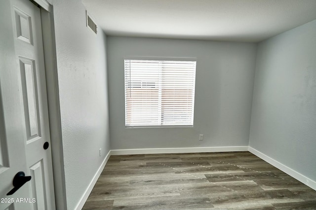 empty room with baseboards, wood finished floors, visible vents, and a healthy amount of sunlight